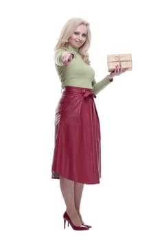 in full growth. elegant woman with a gift box pointing at you. isolated on a white background