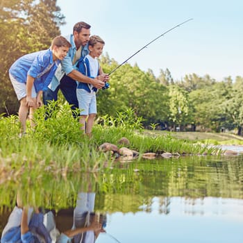 Teaching his boys how to fish. a father and his two sons out fishing in the woods