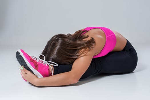 Sport and active lifestyle. Sporty flexible girl fitness woman in pink sportswear doing stretching exercise on light background.