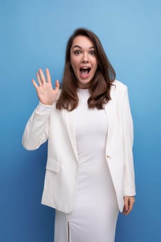 close-up portrait of caucasian brunette with long hair woman in white dress and jacket posing on studio background.