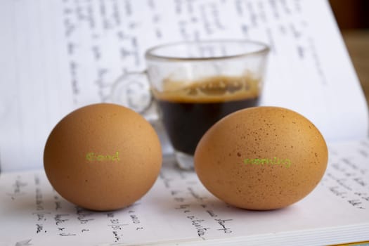 good morning message written on two eggs with a cup of coffee in the background