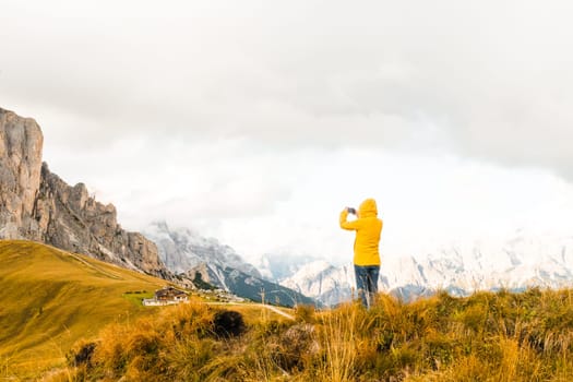 The tourist uses her smartphone to capture the scenic Alpine mountain meadows.