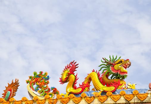 Golden artistic grand yellow Asian dragon statue on the roof of a temple