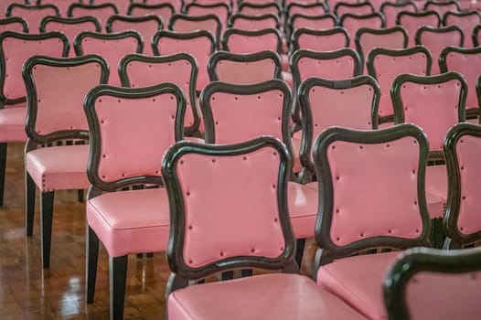 Rows of empty pink cushioned chairs prepared for a warm and welcoming audience.