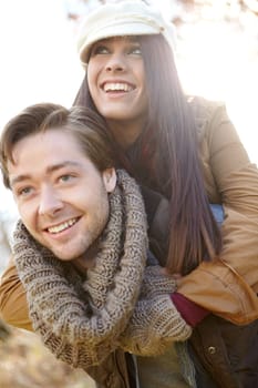 Having fun together. A young man piggybacking his girlfriend while outdoors in the woods