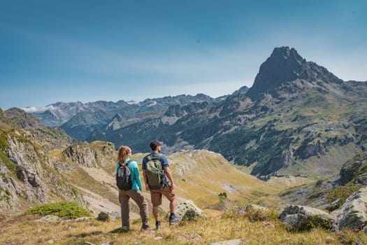 Young Attractive Couple looking the panoramic views of the amazing mountains landscape in summer. Discovery Travel Destination and Freedom Concept. High quality photo.