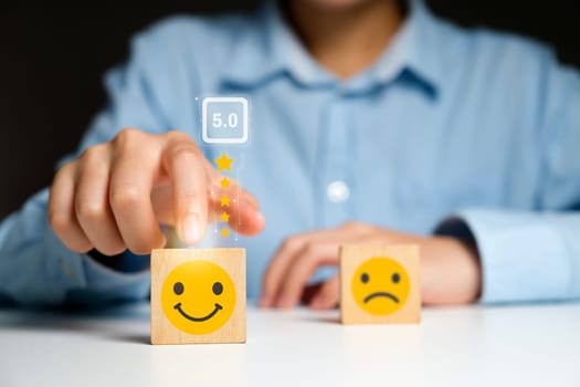 Customer satisfaction concept. Close up customer hand choose smiley face and blurred sad face icon on wood cube, Service rating, satisfaction concept..
