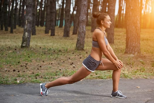 Young woman running outdoors in a city park on. doing warm-up and stretching. with a sun flare