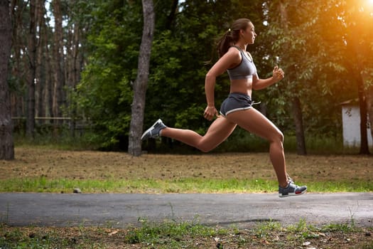Young woman running outdoors in a city park on. motion blurred image color toned image. with a sun flare