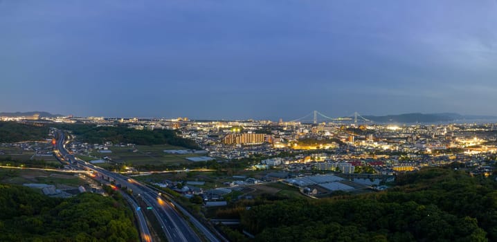 Car lights blur on highway by edge of town in blue hour. High quality photo