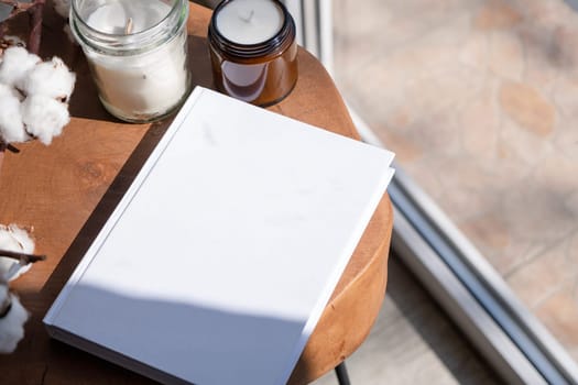 Magazine and book mockup design. Blank magazine on modern wooden table with candles , shadow overlay. Mockup soy wax candle in natural style.