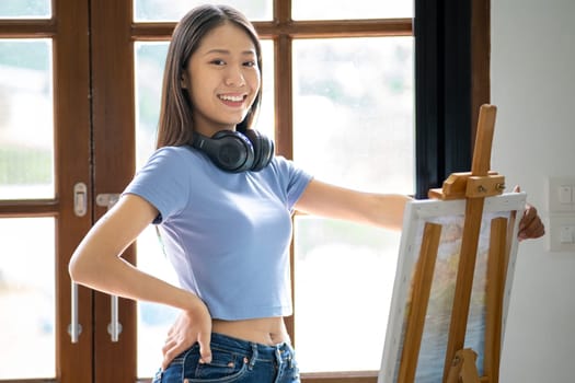 Young happy Asian woman chilling day off painting at home, female artist on canvas at home. hobby drawing. High quality photo