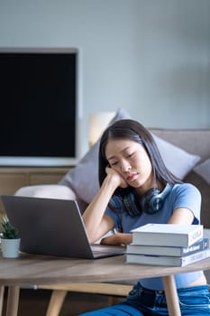 Bored young Asian woman sit at home, employee officer businesswoman working from home bored alone with laptop, high school girl bored at desk. High quality photo