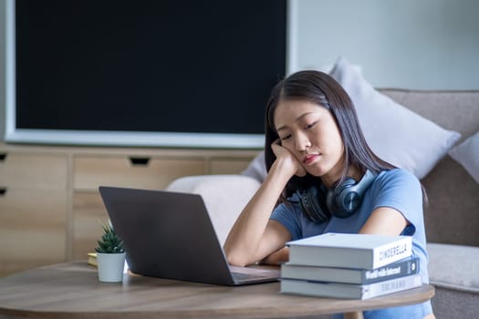 Bored young Asian woman sit at home, employee officer businesswoman working from home bored alone with laptop, high school girl bored at desk. High quality photo