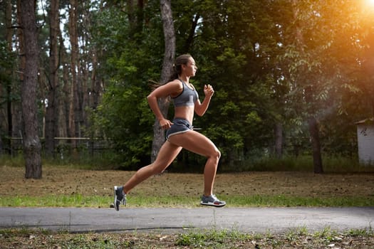 Young woman running outdoors in a city park on. motion blurred image color toned image. with a sun flare