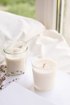 Soy wax aroma candles in jar on bed with lavender flowers. Candle mockup design. Mockup soy wax candle in natural style.
