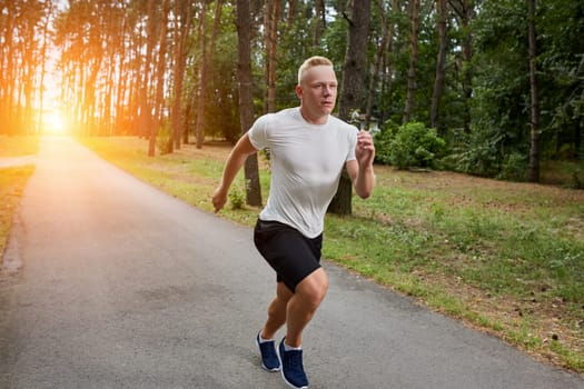 young athlete running in the forest, motion blur. with a sun flare