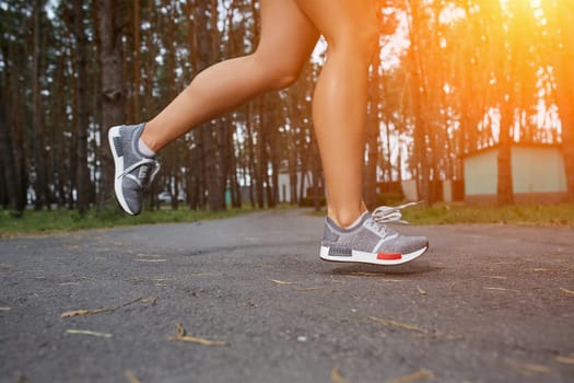 Young woman running outdoors in a city park on. close-up. with a sun flare