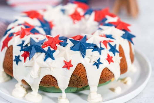 July 4th bundt cake covered with a vanilla glaze and decorated with chocolate stars on a white plate.