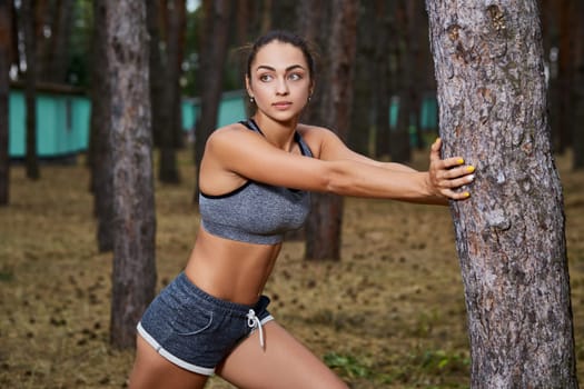 Young woman running outdoors in a city park on. doing warm-up and stretching