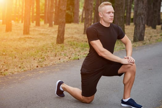 young athlete running in the forest, doing warm-up and stretching. with a sun flare