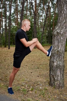 young athlete running in the forest, doing warm-up and stretching