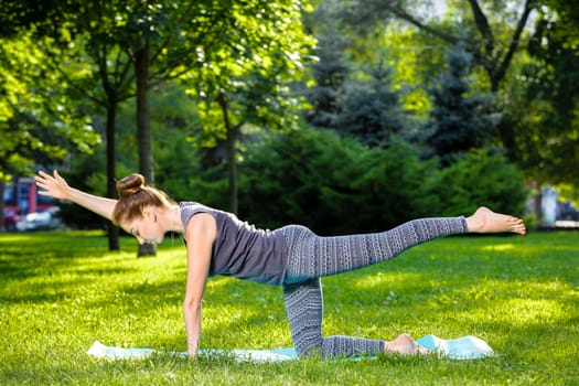 Young fitness woman meditation in a city park.Yoga at sunset in the park. Girl is practicing yoga. Fitness training outdoors. Attractive fitness woman. Workout outdoors. Healthy lifestyle