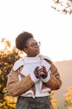 young african woman embraces the outdoors finding peace with tea in the morning, concept of nature's warmth and wilderness lifestyle, copy space for text