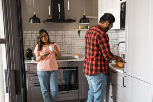 Millennial couple in quarrel and woman with smartphone ignoring each other having breakfast together at home, gadget overuse - communication problem family