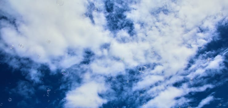 Colorful soap bubbles on a background of blue sky for a children's party. Background image.