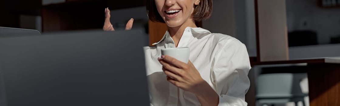 Smiling businesswoman making videocall to friends while working in modern office. High quality photo