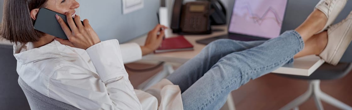 Busy woman worker talk phone with client sit on her workplace in office. Blurred background