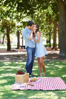 Sharing a romantic afternoon together. A romantic young couple enjoying a picnic in the summer sun
