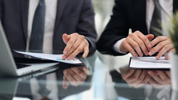 Close up of employees discuss financial paperwork at meeting