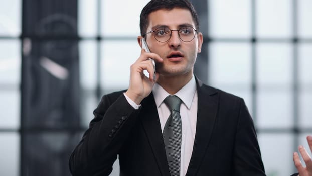 Yes, my business is doing well. a businessman talking on his cellphone while standing in his office.