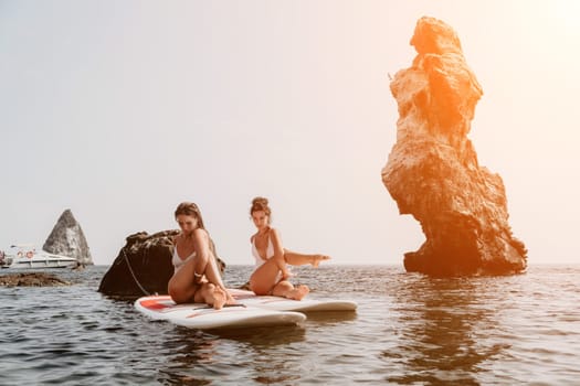 Woman sup yoga. Middle age sporty woman practising yoga pilates on paddle sup surfboard. Female stretching doing workout on sea water. Modern individual hipster outdoor summer sport activity