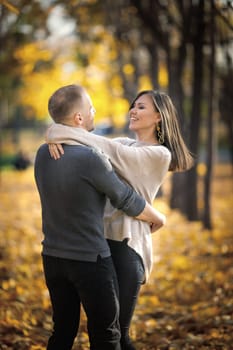 Couple of happy lovers dancing in autumn park on a date. Vertical, copy space