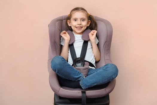 Cute smiling preschool caucasian girl strapped in car seat looking at camera.