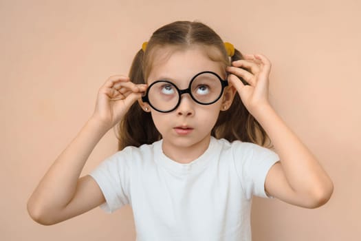 Confused little girl of primary school age put on eyeglasses for the first time.