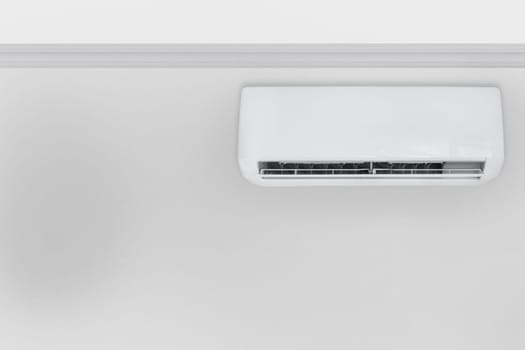 Front view on white air conditioner hanging from the ceiling on the side wall, big copy space.