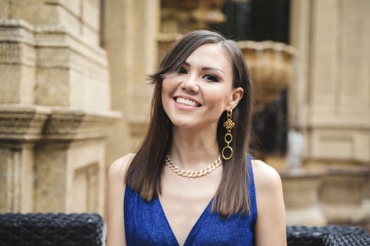 Mixed race young smiling woman in blue dress look at camera outdoor portrait.