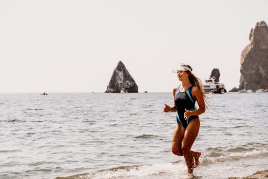 Woman beach vacation photo. A happy tourist in a blue bikini enjoying the scenic view of the sea and volcanic mountains while taking pictures to capture the memories of her travel adventure