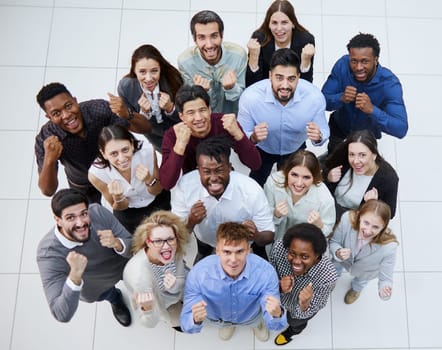 large group of young people looking up with clenched fists celebrating victory