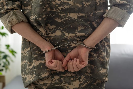 Handcuffed soldier, arrested male army officer in dark prison cell.