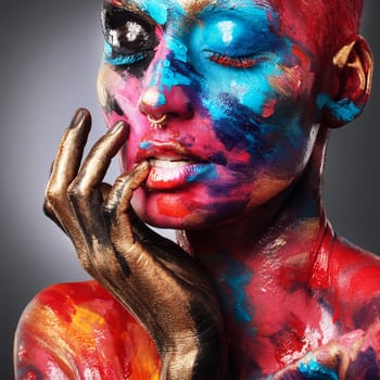Create your own rainbow. an attractive young woman posing alone in the studio with paint on her face