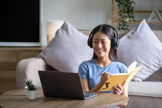 Portrait of young beautiful teenager happy funny Asian woman holding a book and listen the music, relaxing cute Asian chilling at home. High quality photo