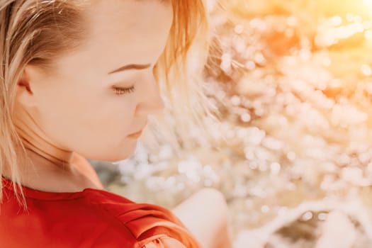 Woman travel sea. Young Happy woman in a long red dress posing on a beach near the sea on background of volcanic rocks, like in Iceland, sharing travel adventure journey