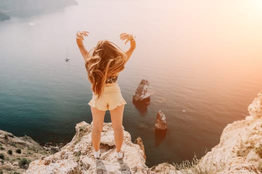 Woman travel sea. Happy tourist taking picture outdoors for memories. Woman traveler looks at the edge of the cliff on the sea bay of mountains, sharing travel adventure journey.