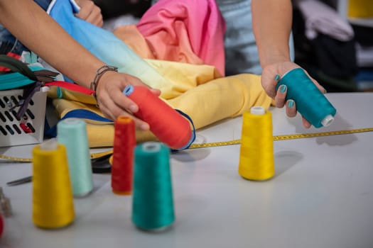 Young clothing designers select the color of threads that will be used to sew the new spring collection. At work in the back of the sewing studio.