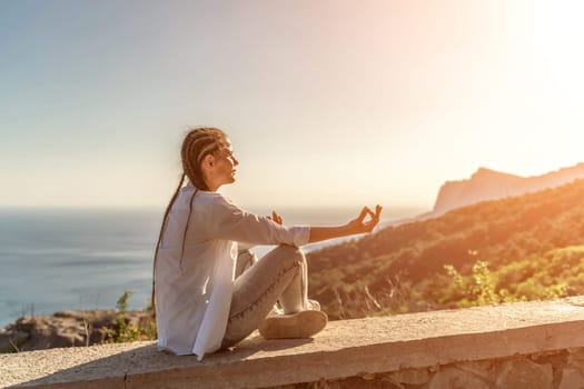 Yoga woman mountains. Profile of a woman doing yoga in the top of a cliff in the mountain. Woman meditates in yoga asana Padmasana.